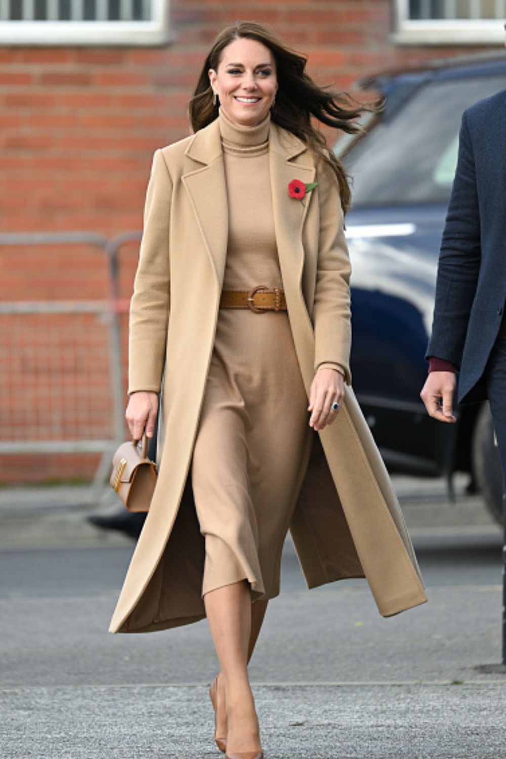 Catherine, Princess of Wales wearing a camel tonal look featuring her regular  camel coat over a dress with tan accessories.