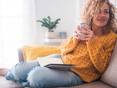 Woman reading book with cup of tea.