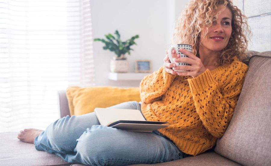 Woman reading book with cup of tea.