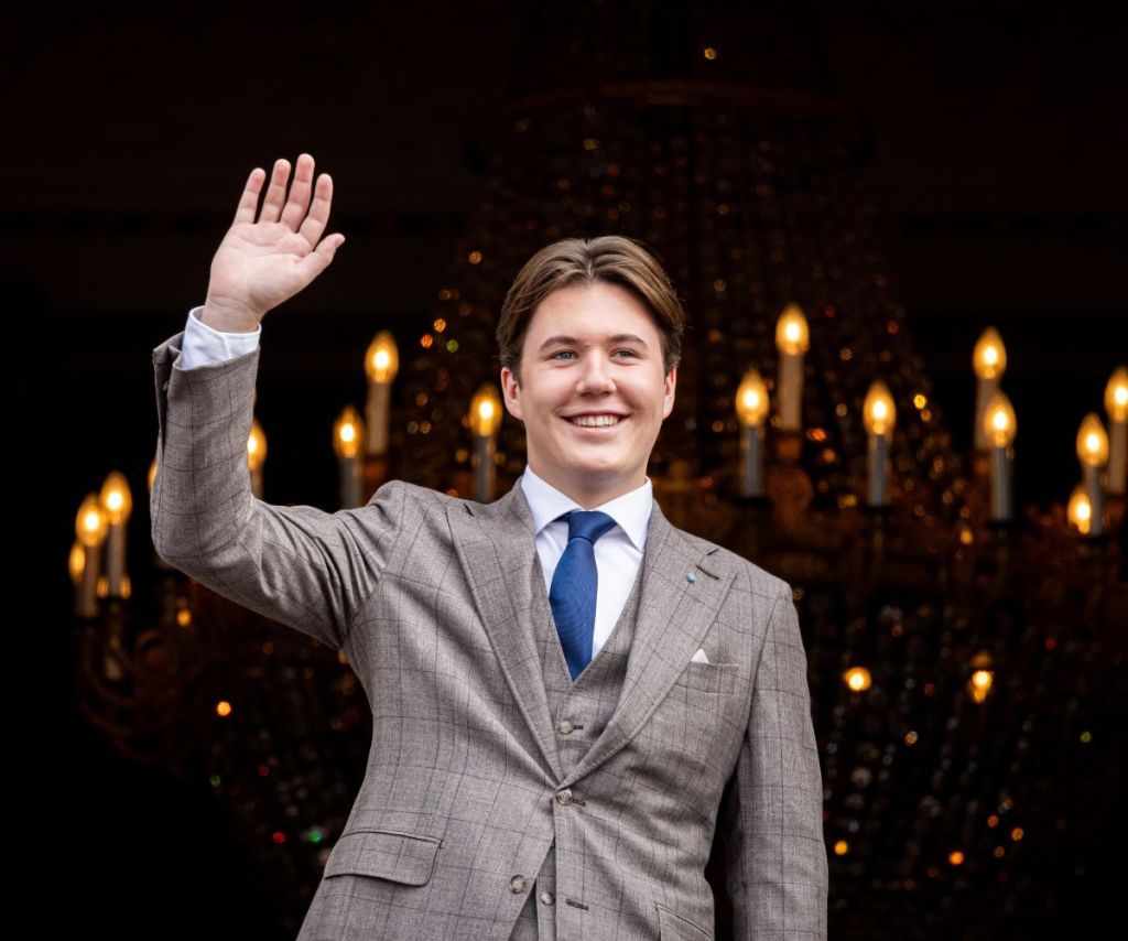 Danish Prince Christian smiles and waves wearing a suit with blue tie