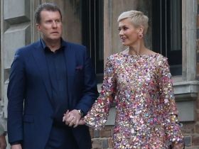 Pete, in a blue suit, and Jess, in a sequin dress, hold hands