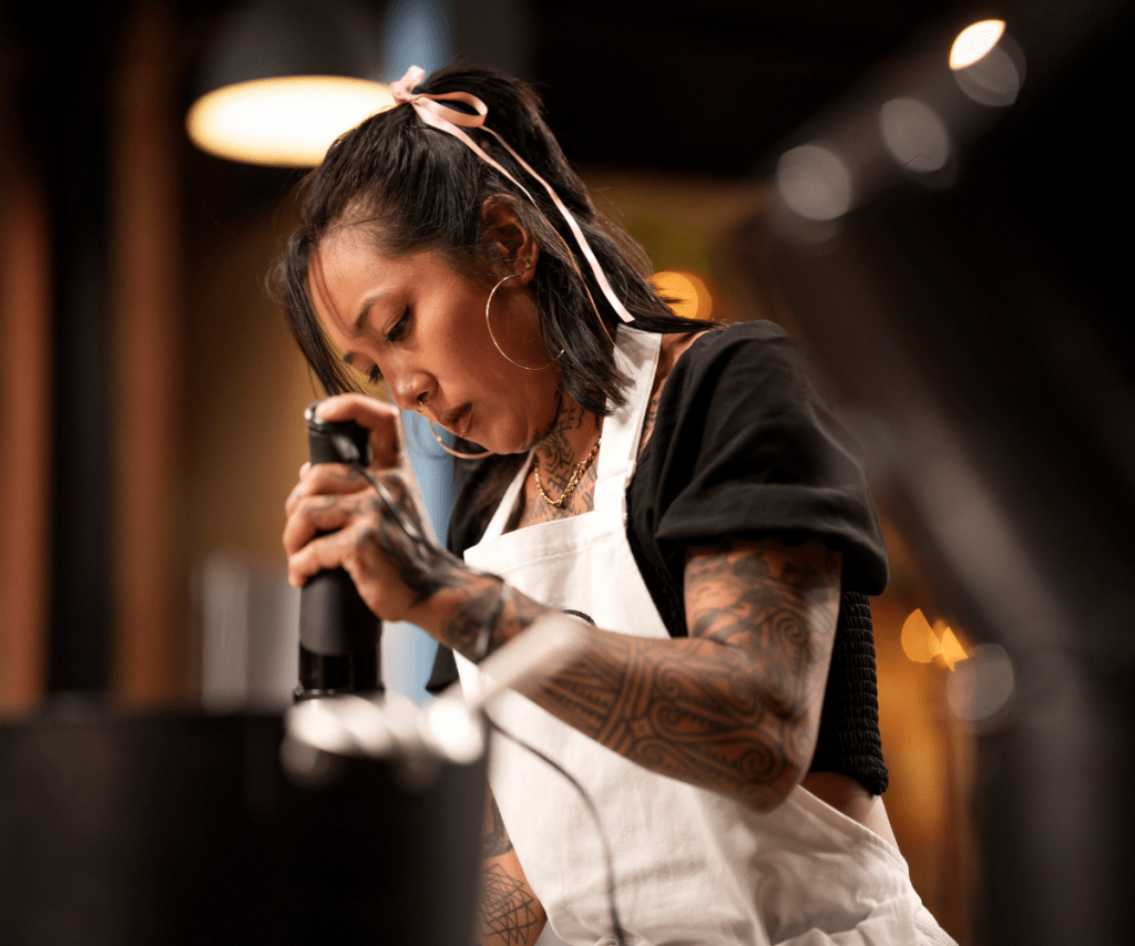 A close up of a focused Nat, cooking in the MasterChef kitchen.