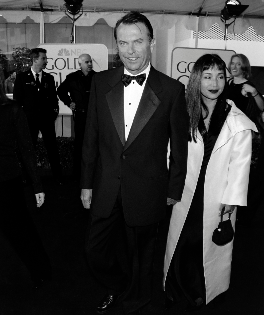 a black and white photo of Sam Neill at the Golden Globes with Noriko. 